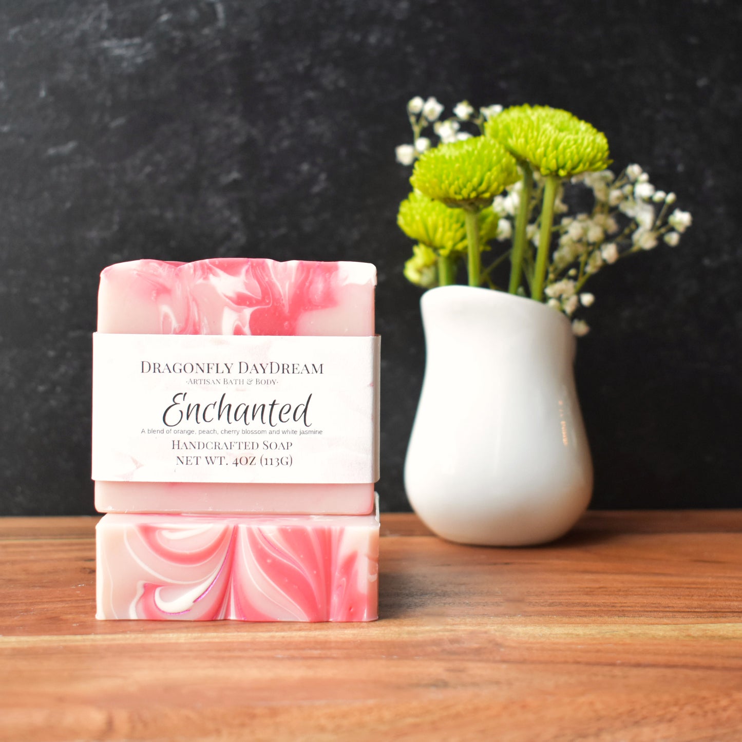 a soap bar with pink and white swirls sitting on a table next to a vase of flowers