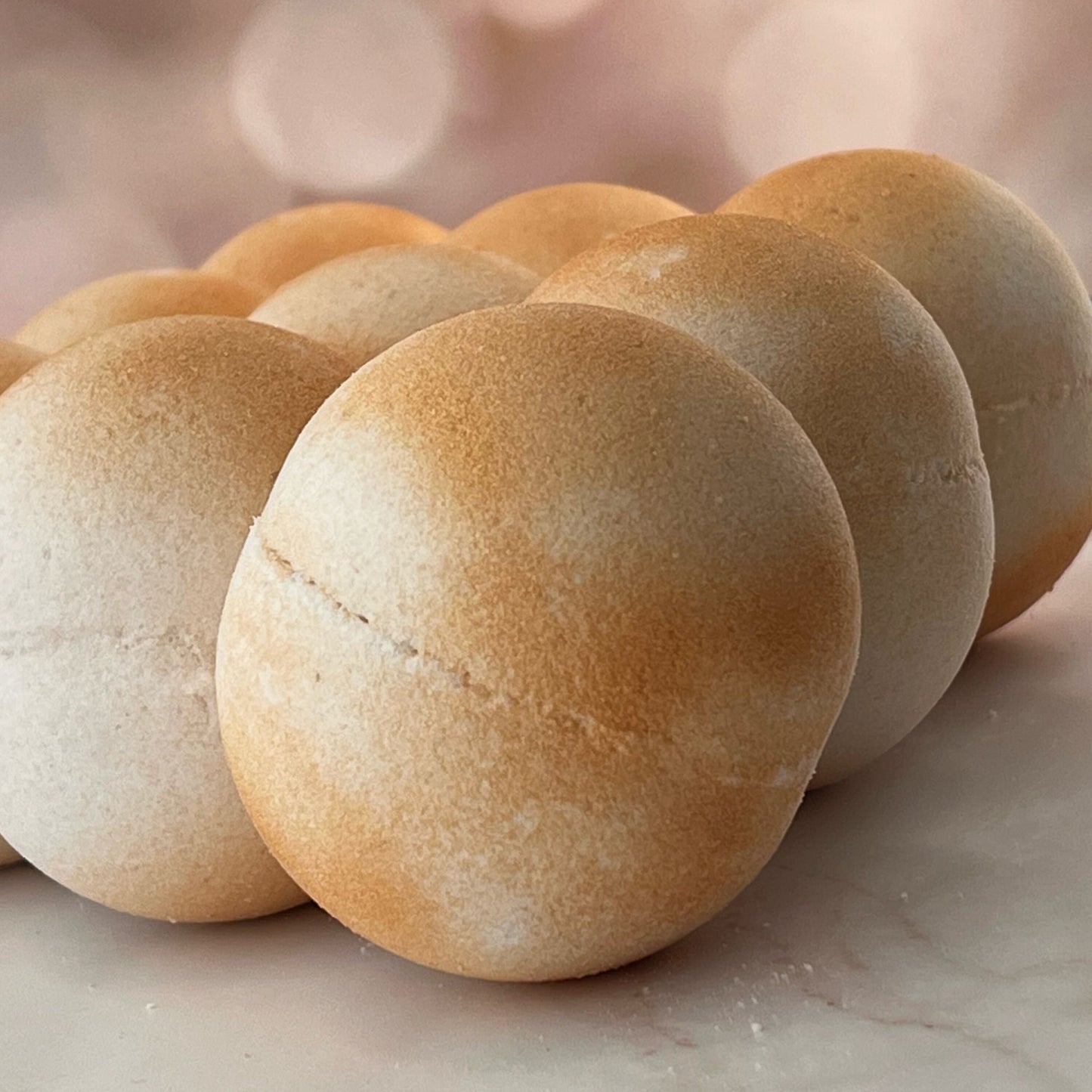 Egyptian Goddess Bath Bombs set of 9, featuring white and gold bath bombs, arranged on a marble background with a blurred fairy light backdrop.
