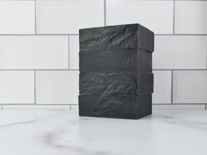 Set of 4 Activated Charcoal Face & body soaps on a marble countertop with a white subway tile background